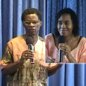 Two people holding microphones in front of a curtain.