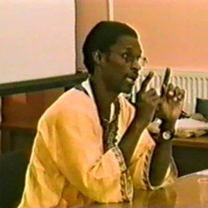 A person in yellow jacket talking on a microphone.