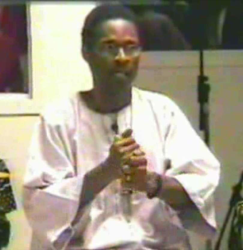 A man in white shirt and glasses holding a flute.