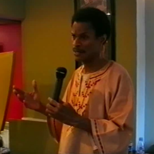 A man in an orange shirt is holding a microphone.