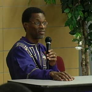 A man holding a microphone while sitting at a table.